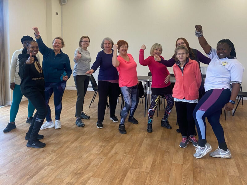 Fitness group in the hall with arms raised