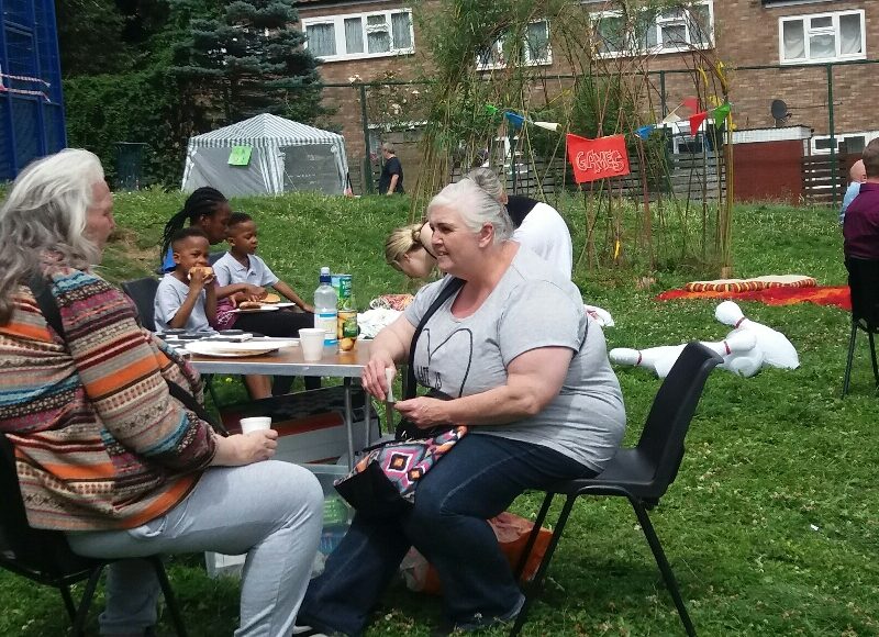 Neighbours talking at tables on grounds outside St Hugh's